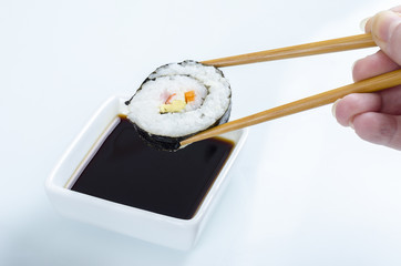 Woman is holding a maki roll over soya.