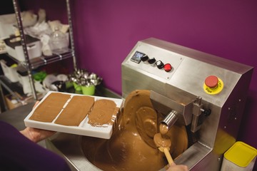 Worker filling mould with melted chocolate