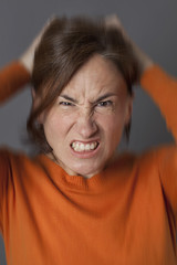 furious middle aged woman pulling out her hair, blurred effects