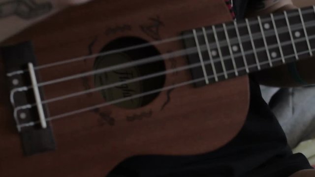 Tattooed guy plays on ukulele
