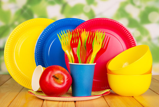 Bright Disposable Plates, Cups, Plastic Bowls, Forks On Abstract Green.