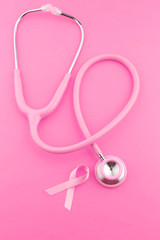 Obraz na płótnie Canvas Stethoscope with pink ribbon on color background. Breast cancer concept