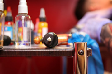 Tattoo machine on wooden table in studio, close up view
