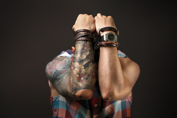 Young tattooed man posing on dark background