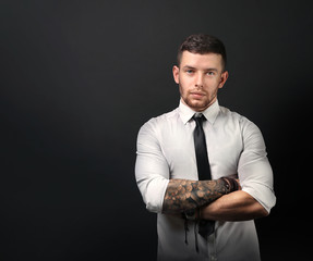 Young tattooed man posing on dark background