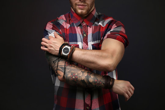 Young tattooed man posing on dark background