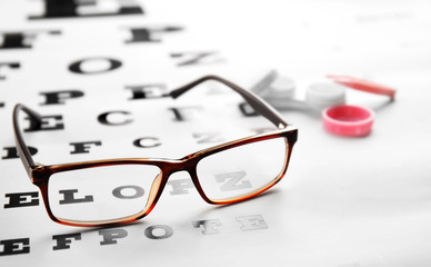 Glasses lying on eye test chart, close up view. Healthy eyes concept