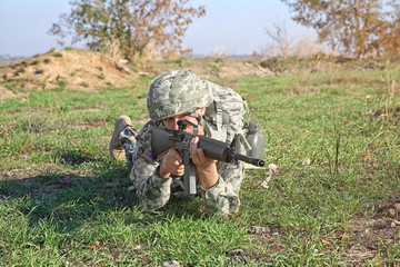 Soldier in camouflage taking aim at military firing range