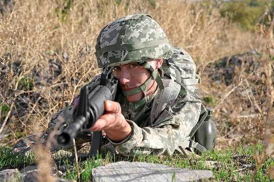 Soldier in camouflage taking aim at military firing range