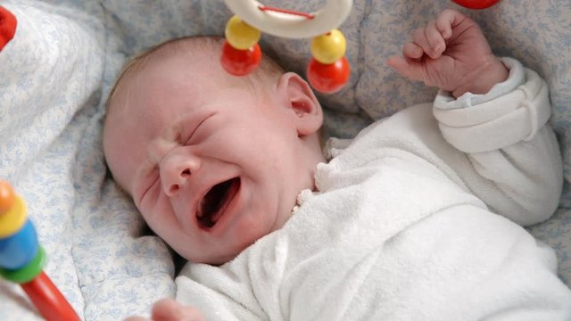 newborn baby crying in bed
