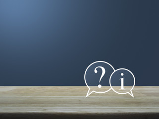 Question mark and information chat icon on wooden table over lig