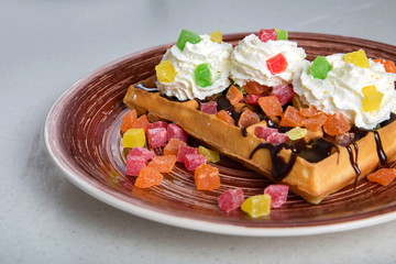 Plate of belgian waffles with cream, candied and chocolate