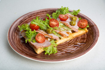 Plate of belgian waffles with ham, tomatoes, herbs and balsamic vinegar