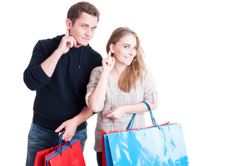 Couple holding shopping bags making can't hear gesture