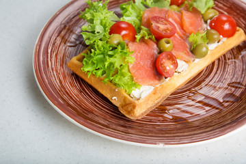 Plate of belgian waffles with salmon, tomatoes, herbs and balsamic vinegar