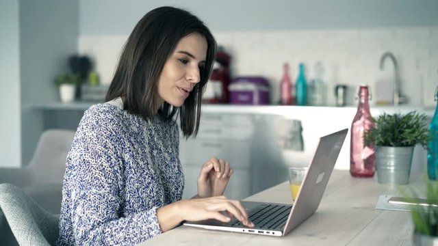 Young pretty woman finish working on laptop and taking break by table at home
