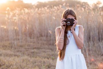 Girl behind camera taking pictures outdoors.