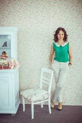 beautiful young woman stands near white chair