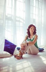 beautiful and gentle young woman sits on white floor