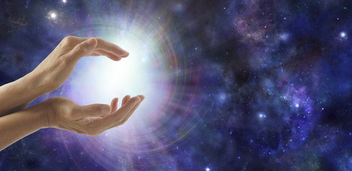 Life Force Energy - side view of female cupped hands with a bright vortexing burst of light on a...