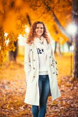 young girl in a light coat on the background of autumn park