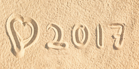 Close up on 2017 written in the sand of a beach with a heart