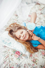 Obraz na płótnie Canvas little cute girl in blue shirt lying on the bed