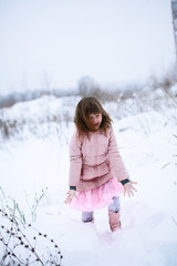 Fototapeta na wymiar The girl in pink jacket gently freezing play outside in the win