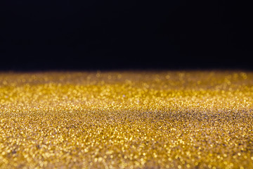 Golden glitter sand rain texture on black, abstract background.