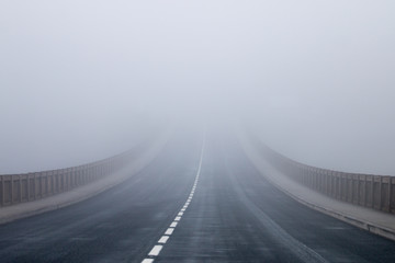 Long asphalt road in the fog