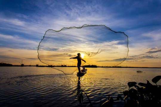 fishermen throwing net fishing in lake on morning sunrise