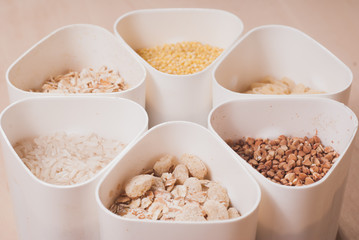 Collection of cereals, grains: rice, oats, buckwheat, millet, wooden table, country kitchen, white capacity,