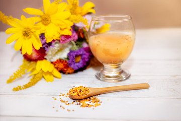 Bee pollen in wooden spoon and glass with liquid pollen