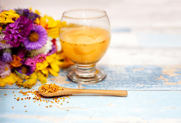 Bee pollen in wooden spoon with pollen liquid in the glass