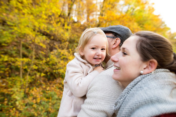 Fototapeta na wymiar Beautiful young family on a walk in autumn forest.