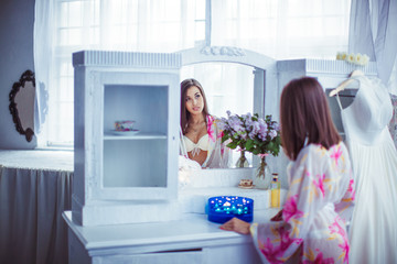 The bride looks at mirror in room