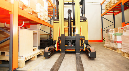 Forklift, shelves and racks with pallets in distribution warehou