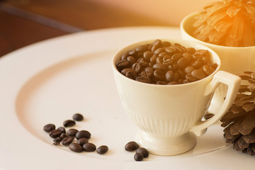 Coffee beans in cup on white plate with warm light effect , vint