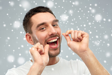 man with dental floss cleaning teeth over snow