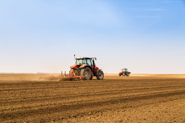 Obraz premium Farmer in tractor preparing land with seedbed cultivator
