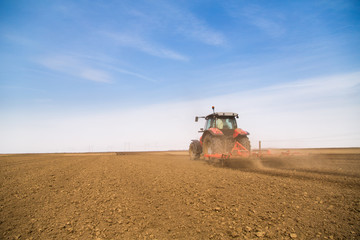 Fototapeta premium Farmer in tractor preparing land with seedbed cultivator