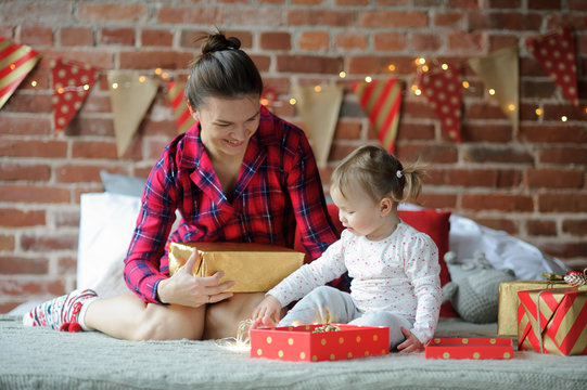 Young woman and her little daughter with delight look at gifts.