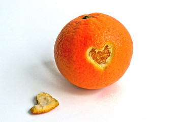 An orange with a heart shaped hole cut out on a white background