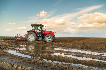 Obraz premium Farmer in tractor preparing land with seedbed cultivator