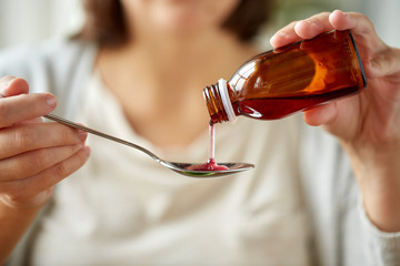 woman pouring medication from bottle to spoon