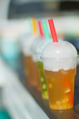 Multi-colored cocktail with dry ice. Straws for drinks. The evaporation of water, the mist over the glass. Blurred background.