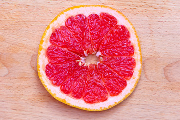 Sliced grapefruit on wooden cutting board. Fresh citrus close up