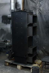 Black solid fuel boiler stands on the floor 