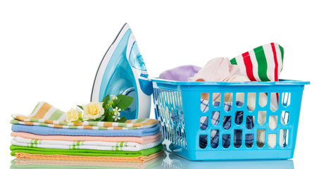 Modern steam iron, pile towels and basket with clothes isolated .