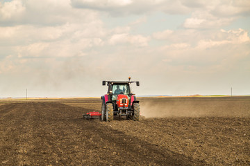 Obraz premium Farmer in tractor preparing land with seedbed cultivator